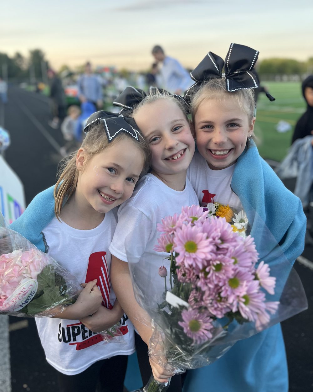 Smiling SuperSquads cheerleaders holding flowers